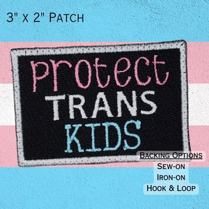 May include: A black iron-on patch with the text "Protect Trans Kids" in pink, gray, and blue lettering. The patch is 3 inches by 2 inches and is shown against a transgender pride flag background. The patch can be sewn on, ironed on, or attached with hook and loop.