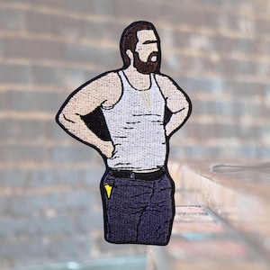 May include: Embroidered patch of a person wearing a white tank top and blue jeans. The person has a beard and is standing with their hands on their hips.