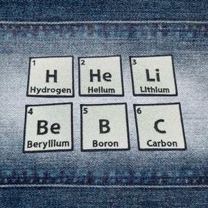 May include: Six square patches with black borders and white backgrounds, each displaying a different element from the periodic table. Elements include Hydrogen, Helium, Lithium, Beryllium, Boron, and Carbon. The patches are arranged on a blue denim background.
