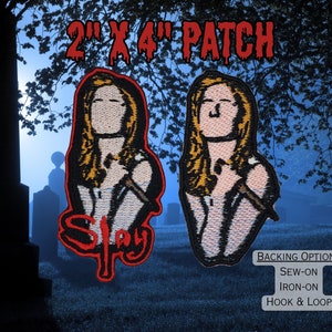 Puede incluir: Un parche bordado de 5 x 10 cm que representa a una mujer sosteniendo un cuchillo con la palabra "Slay" en letras rojas. El parche está disponible con opciones de respaldo de coser, planchar y velcro.