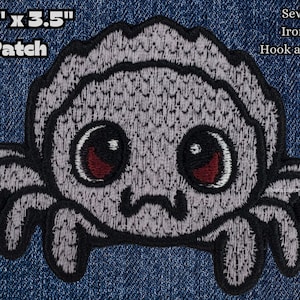 May include: A gray embroidered spider patch with large black eyes and red pupils. The patch is 2.5 inches by 3.5 inches and can be sewn on, ironed on, or attached with hook and loop.