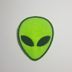 May include: Green felt alien head patch with black eyes.