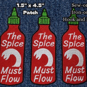 Könnte beinhalten: Drei rote und weiße gestickte Bügelbilder in Form von scharfen Saucenflaschen. Jeder Patch trägt die Aufschrift "The Spice Must Flow". Die Patches sind 1,5 Zoll mal 4,5 Zoll groß.
