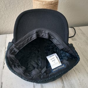 May include: A black, quilted cap with ear flaps. The interior features a quilted lining and a tag that reads "PENDLETON". The cap is designed to provide warmth and protection from the elements.