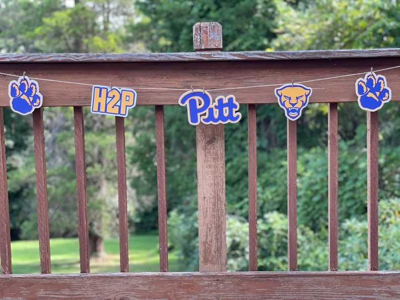 May include: A banner with blue and gold decorations, including a paw print, the text "H2P", the text "Pitt", and a panther head.