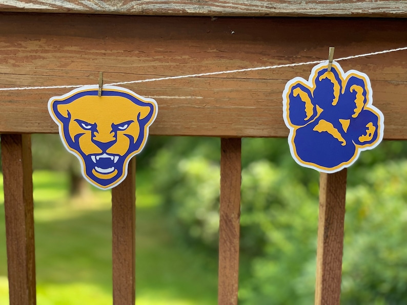 May include: A string of pennants with a blue paw print and a yellow panther head. The paw print is outlined in white and the panther head is outlined in black.