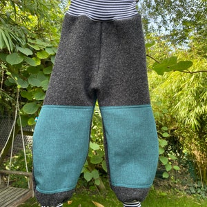 Könnte beinhalten: Graue und türkisfarbene Kinderhose mit einem gestreiften Bund und Bündchen. Die Hose hat ein Patchwork-Design mit einem grauen Oberteil und türkisfarbenen Unterteilen.