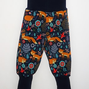 Könnte beinhalten: Marineblaue Babyhose mit einem bunten Fuchs- und Blumenmuster. Die Hose hat einen breiten elastischen Bund und gekrempelte Beine.