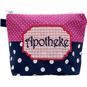 Puede incluir: Pequeño neceser rectangular con cremallera blanca y asa azul marino. La mitad superior es rosa con lunares blancos, y la mitad inferior es azul marino con lunares blancos. Un parche de cuadros con la palabra "Apotheke" está cosido en la parte delantera.