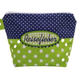 May include: A small, zippered pouch with a two-tone polka dot design. The top half is navy blue with white dots, and the bottom half is lime green with white dots. An embroidered oval patch with the word "Reisefieber" is on the front.