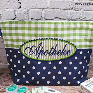 Op de afbeelding: Een groene en witte ruitjesstof met rits met een blauwe en witte stippenstof onderkant. De tas heeft een geborduurde ovaal met het woord "Apotheke" in groene letters.