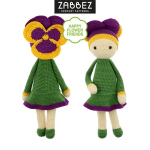 Peut inclure: Deux poupées en crochet avec des chapeaux de fleurs jaunes et violettes. Les poupées portent des robes vertes avec des bordures violettes. Le texte "HAPPY FLOWER FRIENDS" est dans une bulle de dialogue au-dessus des poupées.