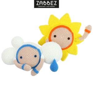 Puede incluir: Un sol de crochet con un cuerpo amarillo, rayos naranjas y una cara marrón. Una nube de crochet con un cuerpo blanco, detalles azules y una cara marrón. Tanto el sol como la nube están sonriendo.