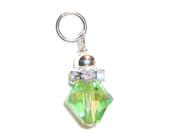 Pode incluir: Um berloque de prata com um pingente de cristal verde e detalhes de cristal transparente. O berloque está preso a um anel de salto de prata.