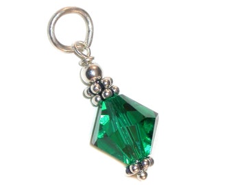 Pode incluir: Um berloque de prata com uma conta de cristal verde e contas de prata. O berloque tem um laço na parte superior para prender a uma pulseira ou colar.