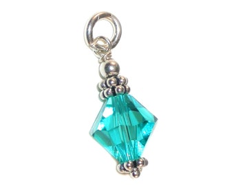 May include: A silver charm featuring a turquoise crystal bead. The bead is faceted and has a silver cap at the top and bottom.