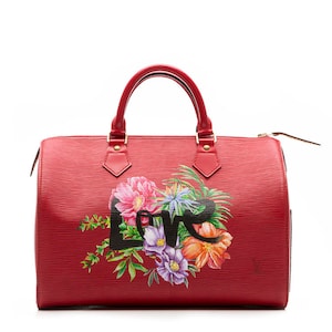 May include: A red leather Louis Vuitton Speedy handbag with a floral print and the word "Love" in black lettering.