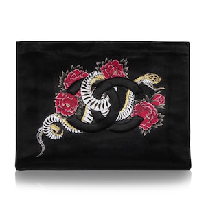 May include: Black leather clutch with a large embroidered snake and red roses design. The Chanel logo is in the center of the snake.