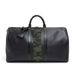 May include: Black leather travel bag with a green camouflage stripe and gold initials "K.R." on the front.
