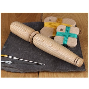May include: A wooden tool for winding thread, with a long, cylindrical handle and a small, round knob at one end. Two wooden butterfly-shaped thread winders are also included, one with yellow thread and one with green thread.