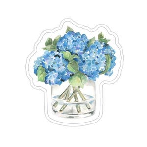 Könnte beinhalten: Aquarell-Aufkleber mit einem Strauß blauer Hortensien in einer durchsichtigen Glasvase. Die Blumen haben eine leuchtend blaue Farbe mit grünen Blättern. Der Aufkleber hat einen weißen Rand.