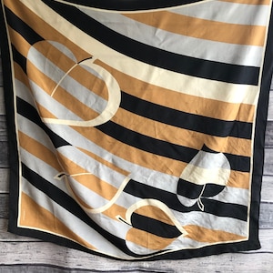 May include: A black, brown and white striped silk scarf with a geometric design of stylised leaves. The scarf has a subtle sheen and a soft drape.