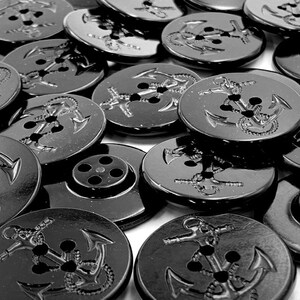 Puede incluir: Primer plano de un grupo de botones negros con un dise&ntilde;o de ancla. Los botones son brillantes y tienen una superficie lisa.