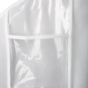 Op de afbeelding: Een witte kledingzak met een transparant plastic venster aan de voorkant. De zak heeft een ritssluiting en een klein transparant plastic zakje aan de voorkant.