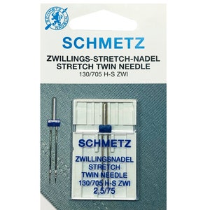 Puede incluir: Un paquete de dos agujas gemelas de estiramiento plateadas para m&aacute;quinas de coser. El paquete est&aacute; etiquetado con "Schmetz" y "Zwillings-Stretch-Nadel Stretch Twin Needle 130/705 H-S Zwi 2,5/75".