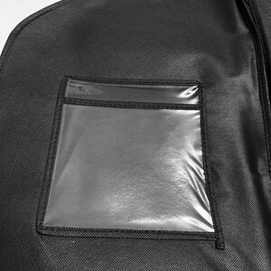 Pu&ograve; includere: Custodia per abiti nera con una finestra rettangolare trasparente. La borsa ha una chiusura a cerniera ed &egrave; appesa a un gancio di metallo. Il materiale ha un aspetto strutturato.