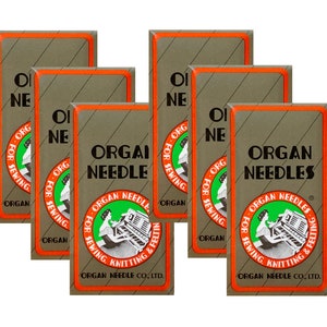 May include: Six packs of Organ needles for sewing, knitting, and felting. The packs are brown with orange trim and feature a green circle with a woman sewing on an organ.