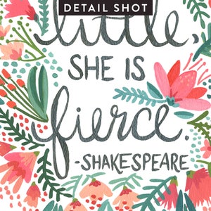 May include: A white background with a floral wreath surrounding the text "little, she is fierce. -SHAKESPEARE". The flowers are pink, red, and green.
