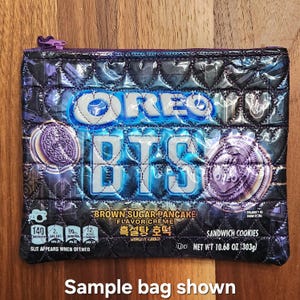 May include: A rectangular zippered pouch made from a repurposed Oreo BTS Brown Sugar Pancake flavor creme sandwich cookie package. The exterior features a quilted texture, a purple zipper, and the original blue and black branding.
