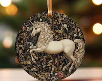 Könnte beinhalten: Runder Weihnachtsschmuck mit einem weißen Einhorn mit fließender Mähne und Schweif, vor einem dunklen Hintergrund mit floralen und Baumdetails. Das Jahr "2025" ist unten aufgedruckt. Ein goldenes Band ist zum Aufhängen befestigt.