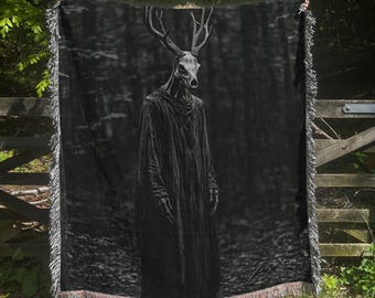 May include: A black and white tapestry depicting a hooded figure with a deer skull mask standing in a dark forest. The figure is wearing a long, flowing robe and has antlers on its head.