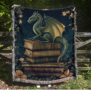 May include: A green dragon with gold wings perched on a stack of old, leather-bound books. The dragon is set against a dark blue background with stars and a few flowers.