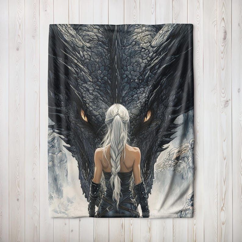 May include: A fantasy-themed blanket featuring a woman with long white hair facing a large black dragon. The dragon's eyes are a bright orange. The woman is wearing a black outfit with leather accents. The background is a misty, mountainous landscape.