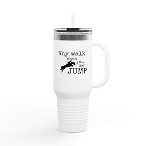 May include: White travel mug with a handle and a straw. The mug features the text "Why walk when you can JUMP" in black, along with a silhouette of a horse and rider jumping over an obstacle. The mug has a silver lid.