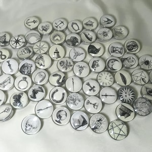 May include: A collection of round, white and black illustrated magnets. The magnets feature various designs, including animals, symbols, and objects. The illustrations are detailed and artistic, creating a unique and eclectic set.