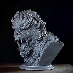 Puede incluir: Busto gris de un hombre lobo gruñendo con pelaje detallado y dientes afilados. La escultura presenta una boca abierta, revelando una lengua y colmillos. El busto está montado sobre una base circular, mostrando un diseño feroz y detallado.
