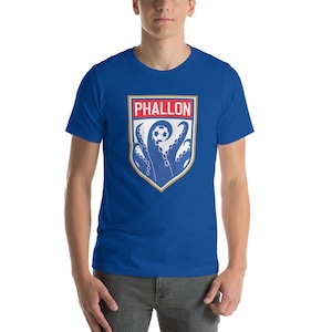 May include: A royal blue t-shirt with a white and blue crest featuring an octopus holding a soccer ball. The crest has the word "PHALLON" in red letters.