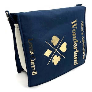 May include: A navy blue canvas tote bag with a gold design featuring playing card suits and the text "Alice's Adventures in Wonderland" and "Lewis Carroll".