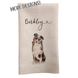 May include: A beige kitchen towel with the name "Barkley" written in black cursive script and a small heart symbol. A watercolor painting of a blue merle Australian Shepherd dog is centered on the towel.