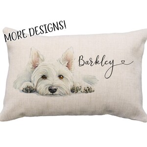 May include: Rectangular beige pillow featuring a watercolor illustration of a white West Highland Terrier dog. The dog is lying down with its head up. The name "Barkley" is written in cursive. Text at the top reads "MORE DESIGNS!"