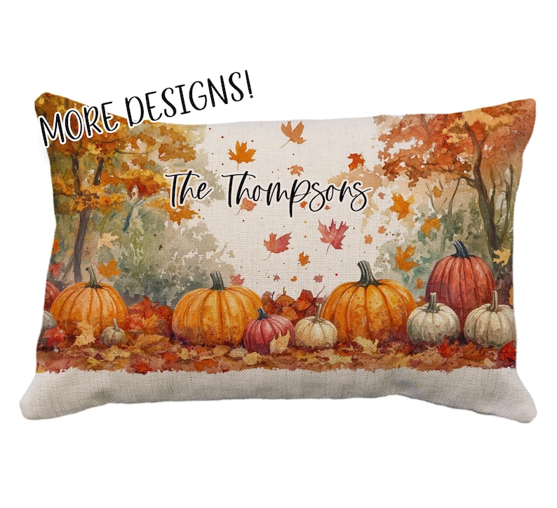 May include: Rectangular decorative pillow featuring a watercolor autumn scene with pumpkins and falling leaves. The pillow has the text "The Thompsons" and "MORE DESIGNS!" in a script font. The pillow is a fall-themed home decor item.