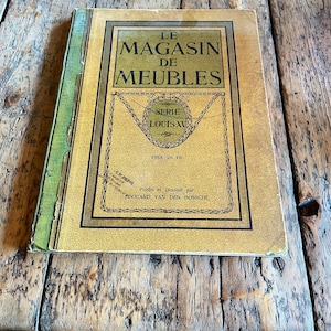 May include: A vintage book cover with a yellow background and a black border. The title is "Le Magasin de Meubles" and the subtitle is "Serie Louis XV". The price is listed as "Prix 20 Fr".