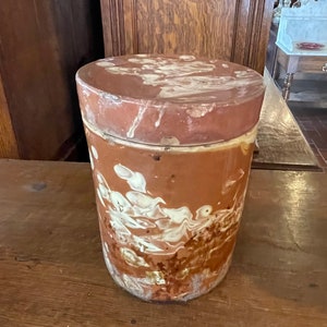 May include: A brown ceramic jar with a white marbled design. The jar has a lid and is approximately 7 inches tall.