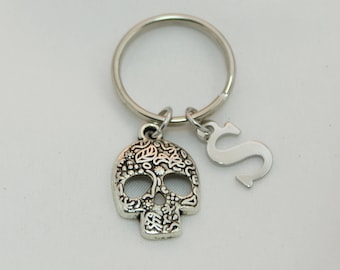 May include: Silver key chain with a detailed sugar skull charm and a letter 'S' charm.