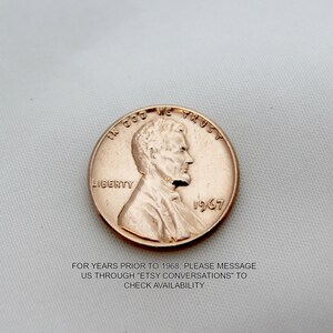May include: A copper-colored 1967 US penny coin with the words "In God We Trust" and "Liberty" inscribed on it. The coin features a profile of Abraham Lincoln.