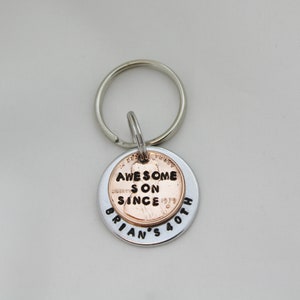 May include: Silver key chain with a copper penny attached. The penny has the words "Awesome Son Since" engraved on it. The silver part of the keychain has the words "Brian's 40th" engraved on it.